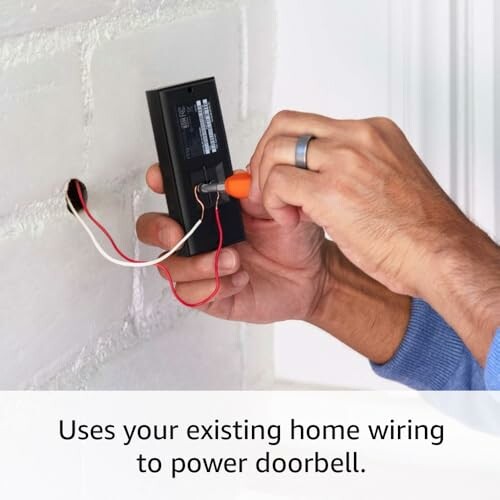 Hand installing a wired doorbell on a wall.