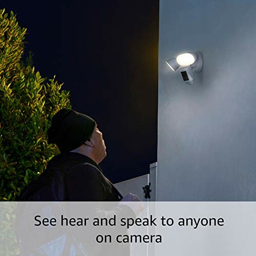 Person looking at outdoor security camera with light at night