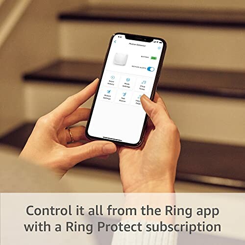 Person holding phone with Ring app open, stairs in background.